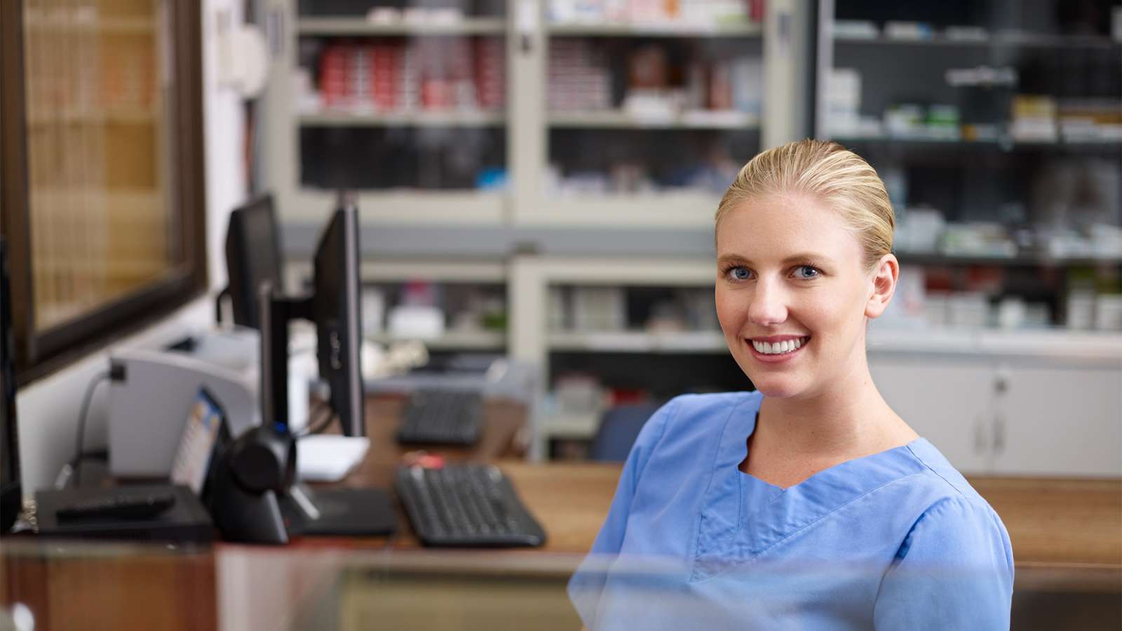 A medical office specialist sits at a desk at a clinic.