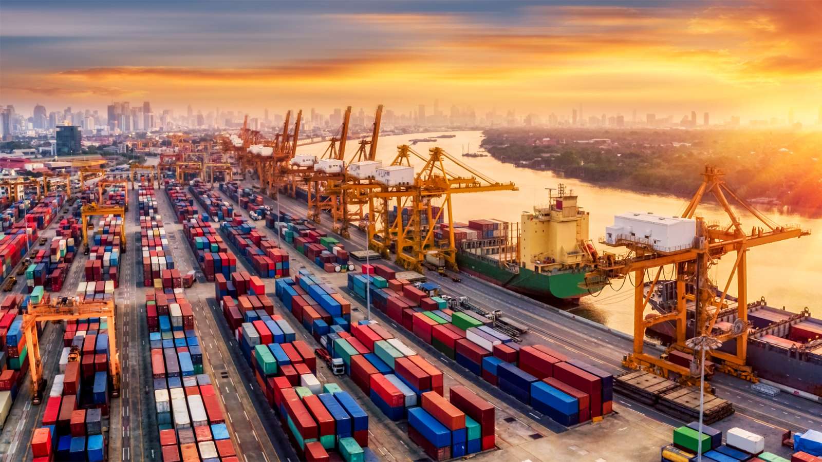 An aerial view of a container port and a shipyard at sunrise.