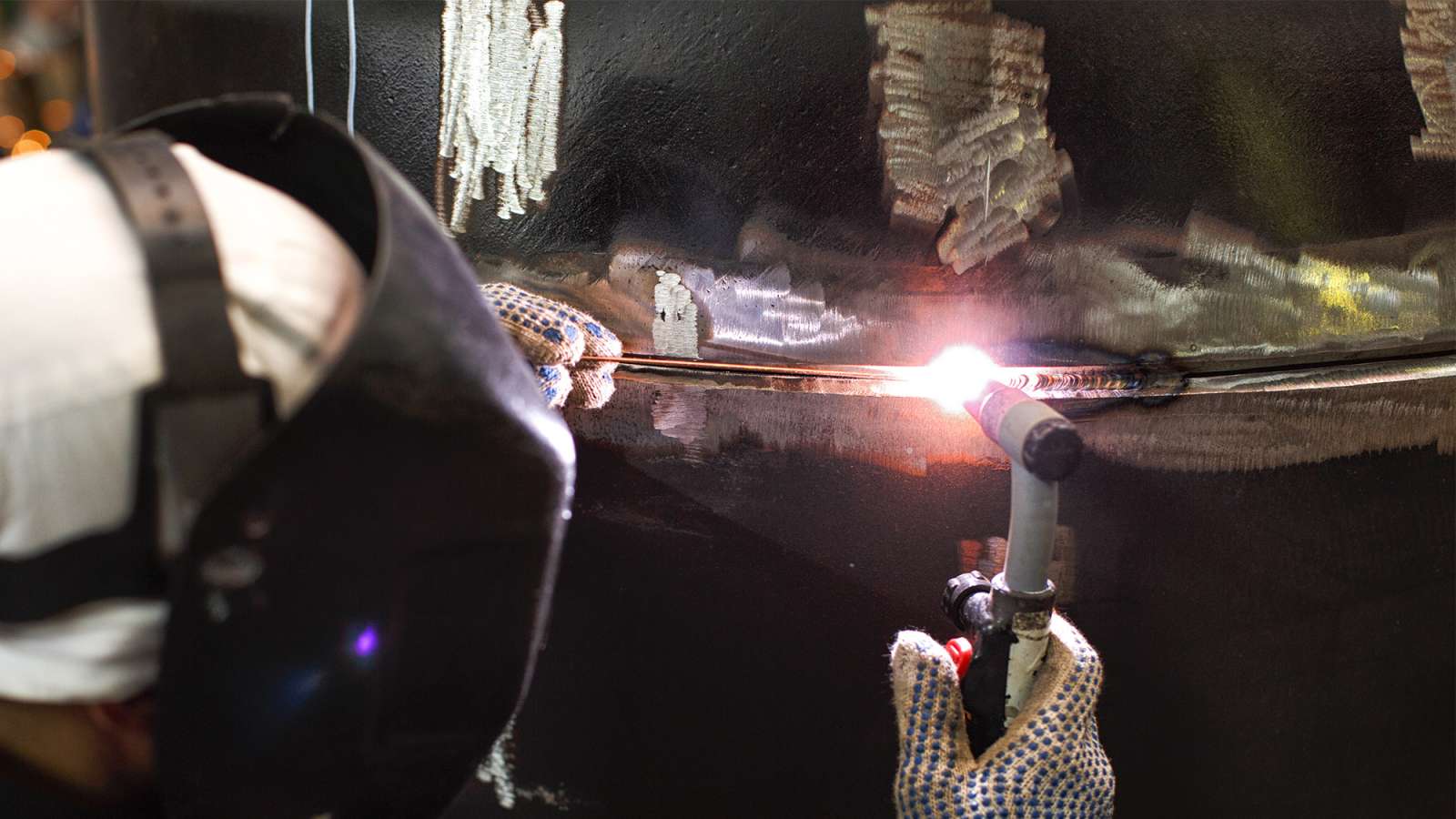 A gas tungsten arc welder is welding a steel pipe.