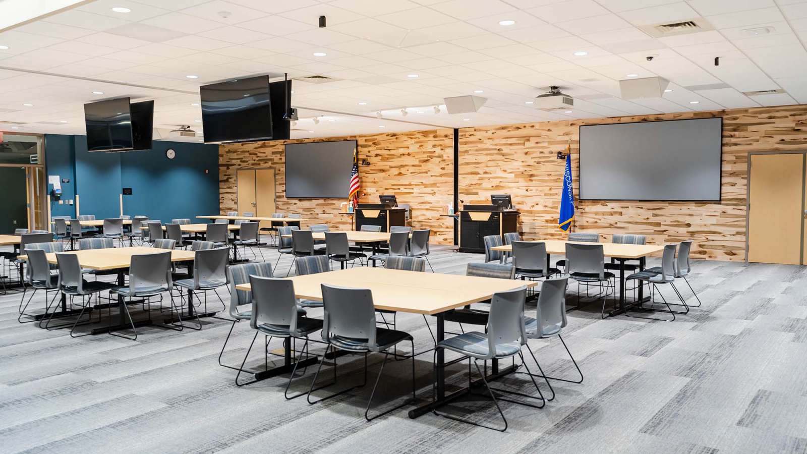 The E101 & E102 conference rooms with the dividing wall opened up, showing a square table configuration with 8 chairs at each table.
