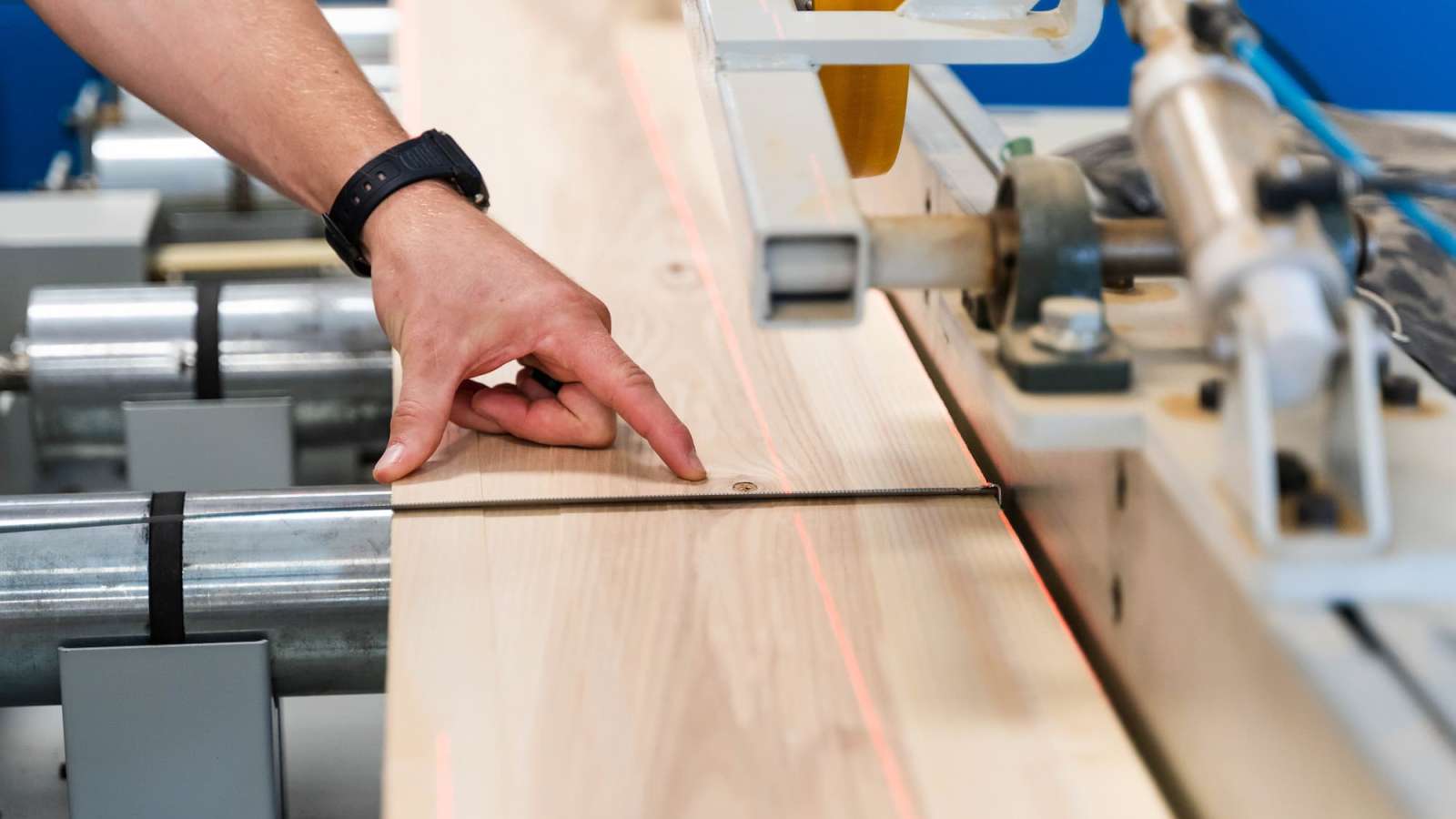 A close-up of lumber passing through a roughing mill, marked by a red laser line.