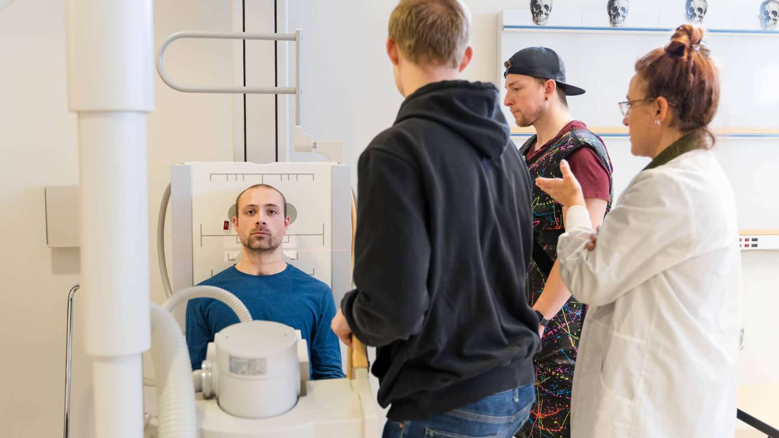 A student acts as the patient while their classmates prepare to conduct imaging of the skull.