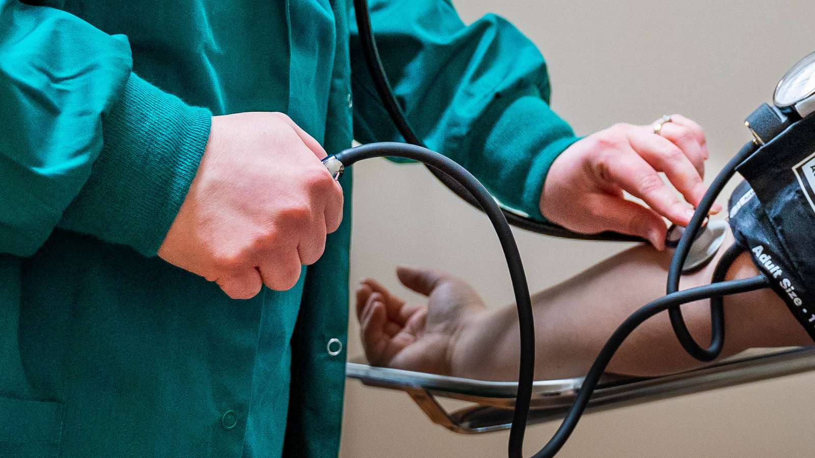 A medical assistant is using a stethoscope to check the pulse and blood pressure of a patient.