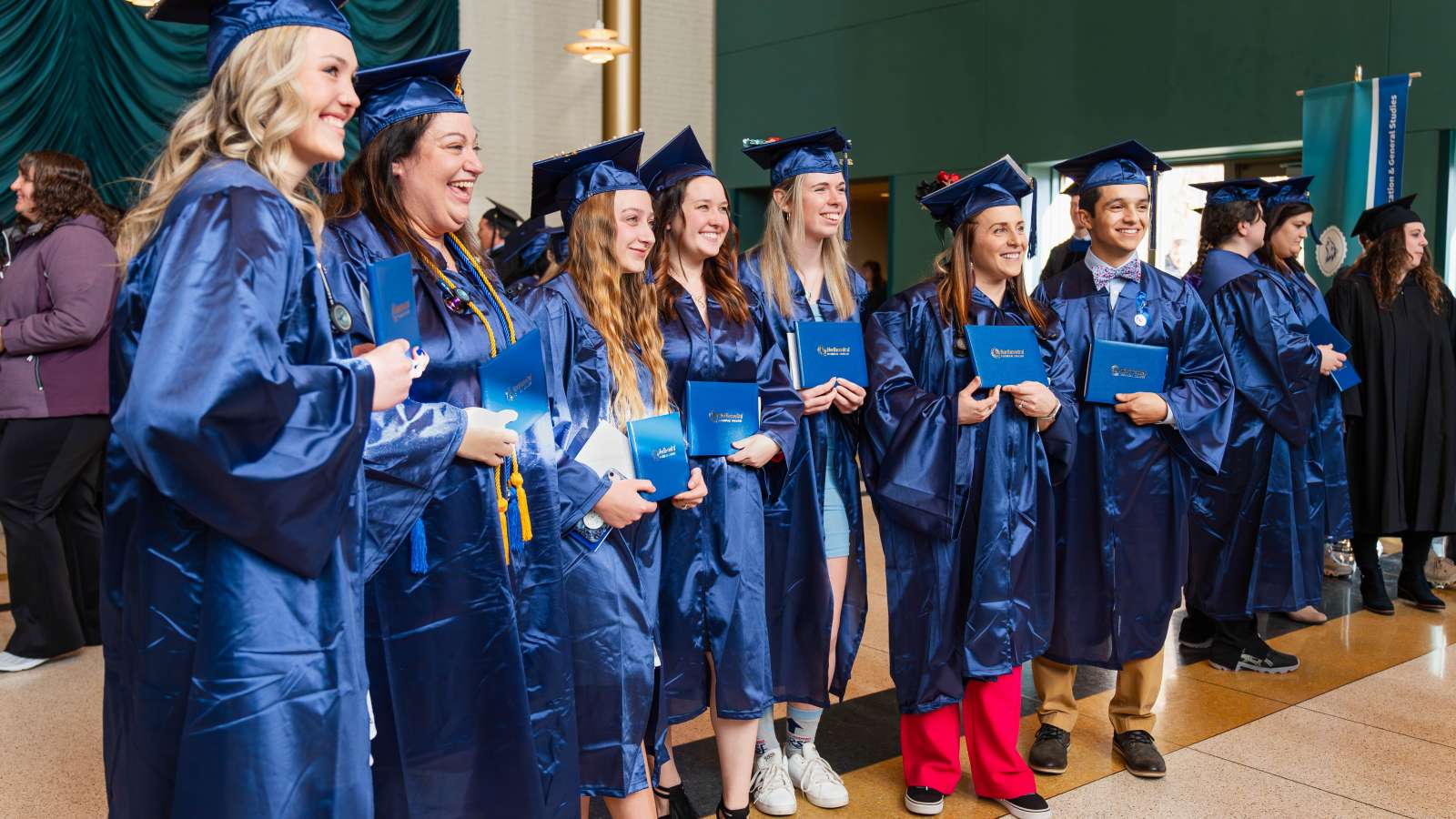 NTC graduates dressed in their caps and gowns, holding their diplomas.