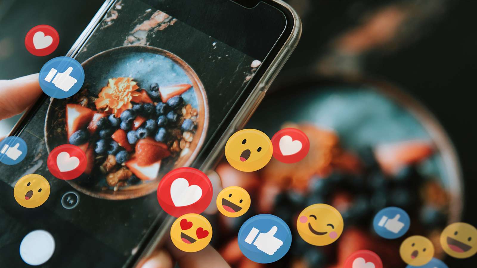 Close-up of a smartphone; blurred second bowl in background, with floating social media icons overlaid in foreground.