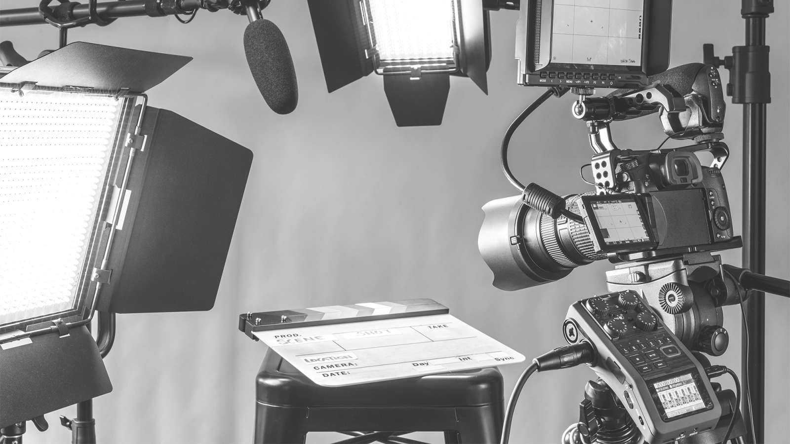 Studio setup with DSLR camera on rig, professional lights and boom microphone surrounding a small table with an open tablet.