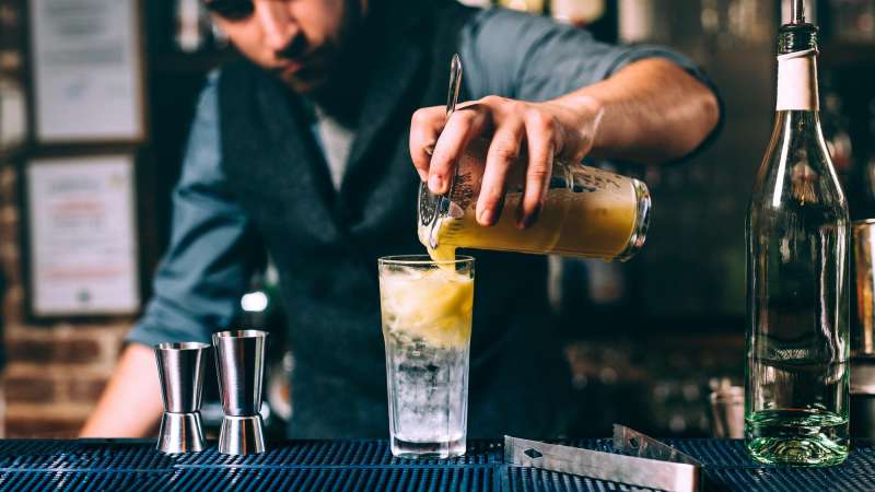Bartender pours a mixed drink into a glass