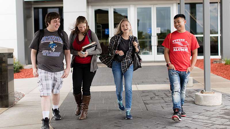 Four students walking together near front entrance of NTC
