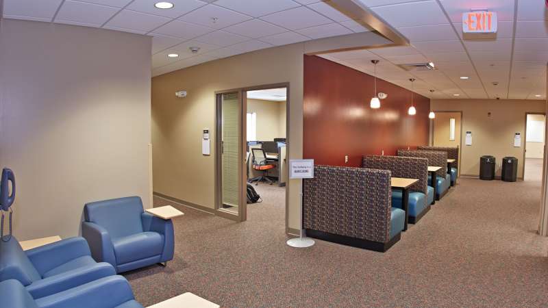 A view of the interior of the Spencer Campus building, featuring booths for students to work in and a view inside an open classroom.