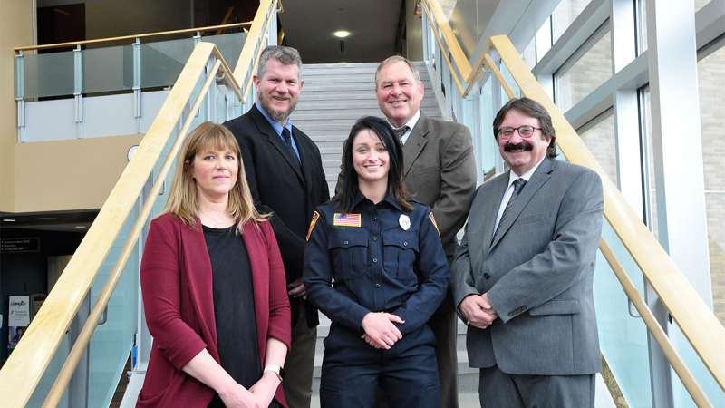 Fink stands in front of her instructors on a staircase