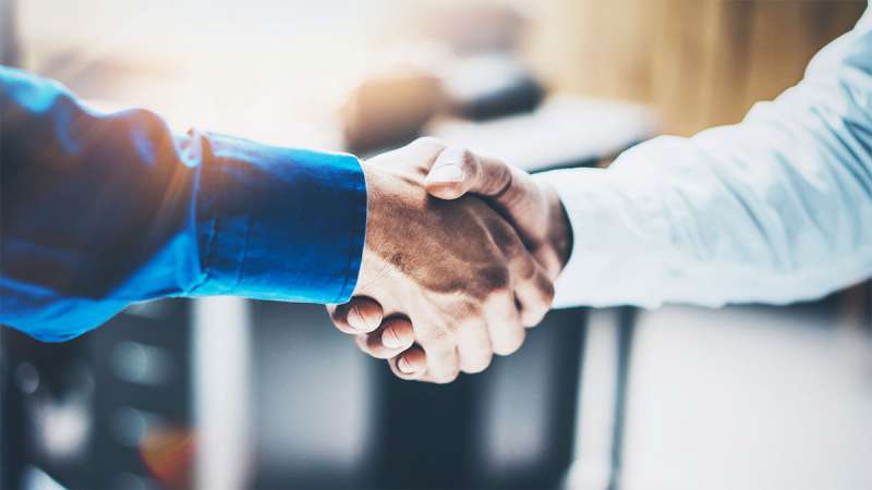 A close up view of two business persons shaking hands.