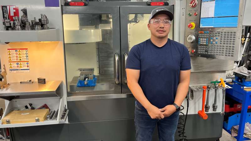 A machine tool student standing in front of equipment in the NTC Machine Tool Lab