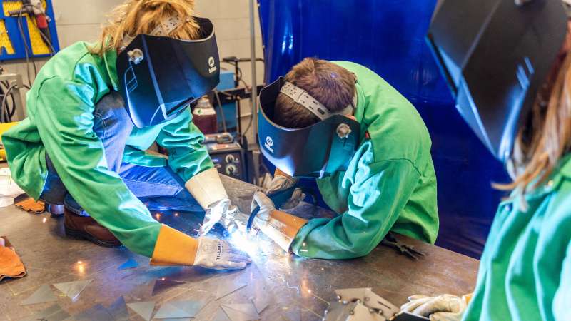 Students welding a project in camp