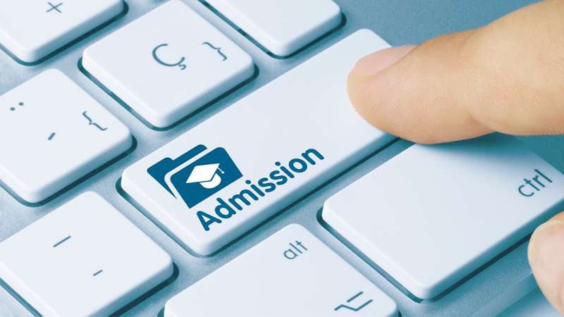 A close up view of a finger pointing at the word Admissions on a keyboard