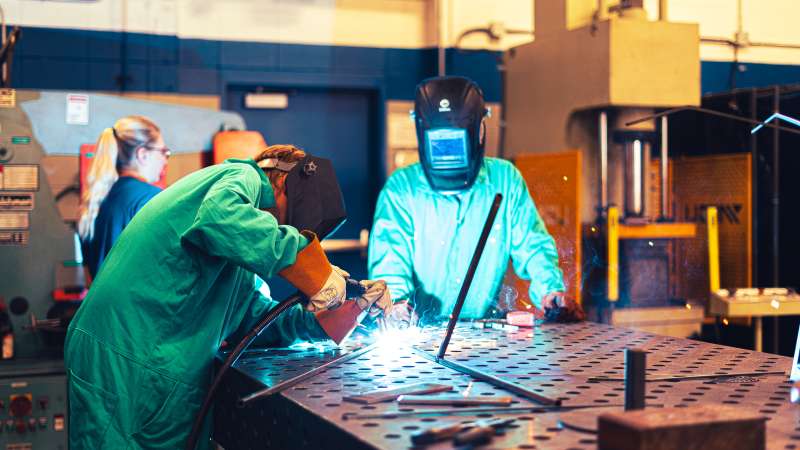 Students working on a welding project. Sparks are flying.