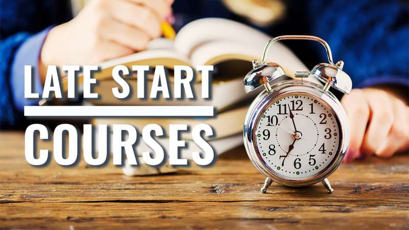 Alarm Clock on Wooden Table With Open Book and Student Writing in Background. Text Overlay Reads ‘Late Start Courses.