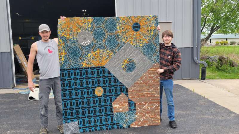 Two students hold up their project as part of NTC's first cohort of floor installation technician certificate