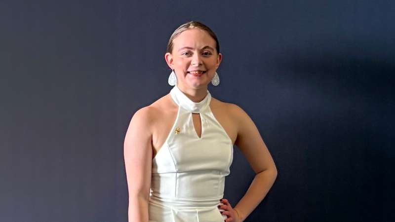 Emilynn smiling while standing in front of a dark gray backdrop.