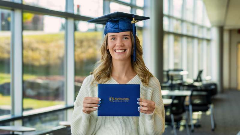 Jade smiling while wearing her graduation cap and holding her diploma.