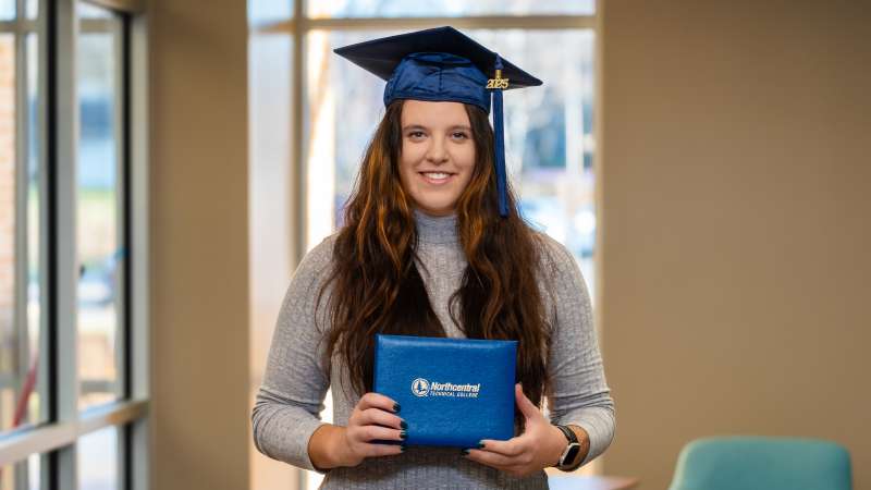 Lana smiling while wearing her graduation cap and holding her diploma.