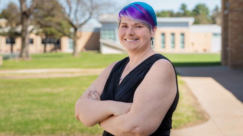 Sarah Watson stands, smiling with arms crossed on a sunny day in the Wausau Campus courtyard