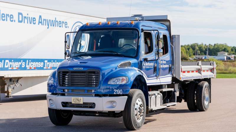 A flatbed training truck parked on the paved driving range.