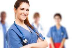 A young medical student stands with her arms crossed with a Stethoscope draped around her shoulders.