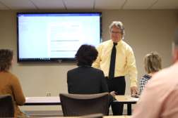 Instructor at front of classroom with students in chairs in front of him