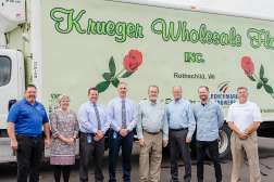Several people stand in front of a truck with Krueger Florists Inc. written on the side.