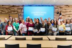 Graduates of Nonprofit Management Institute stand together with their certificates of completion at a graduation ceremony.