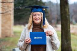 Jennifer posing while wearing an NTC graduation cap and holding her diploma.