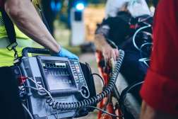 Emergency medical technician operates portable heart monitor during critical patient care scenario.