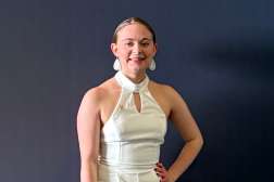 Emilynn smiling while standing in front of a dark gray backdrop.