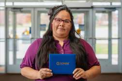 Jalissa smiling while holding her diploma.