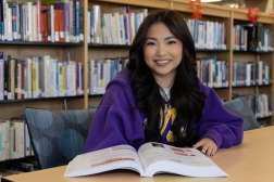 Samyris seated at a library table with a textbook open in front of her