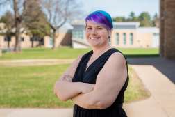 Sarah Watson stands, smiling with arms crossed on a sunny day in the Wausau Campus courtyard