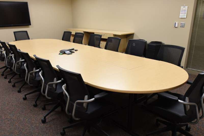 A conference room with one table lined by conference chairs on each side and at the ends.