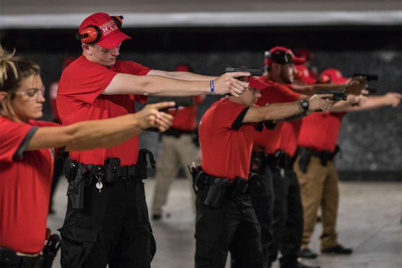 Campus security recruits are doing a training drill at a firing range. They're aiming their firearms at a target