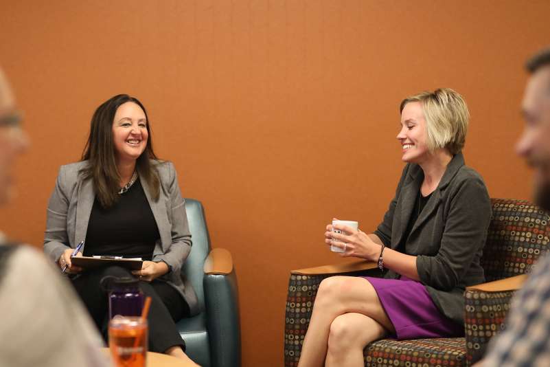 Four businesspeople are in a conference room talking with each other