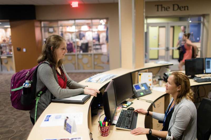 Student stands at the front desk of the Wausau Campus, as she talks to a staff member
