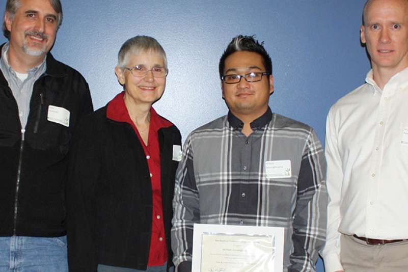 Three people present a scholarship to a student