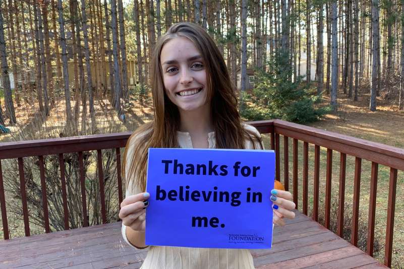 Scholarship Recipient Brianna Besaw holding up a sign that reads: Thanks for believing in me.