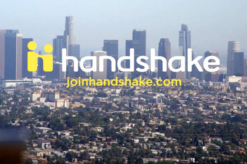 Handshake logo in the foreground with an overhead view of a city in the background.