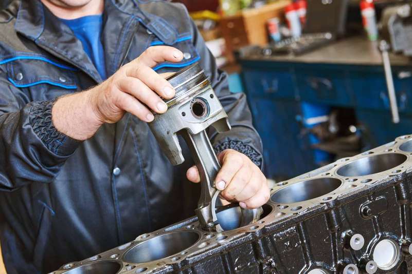 Diesel technician installing piston into engine