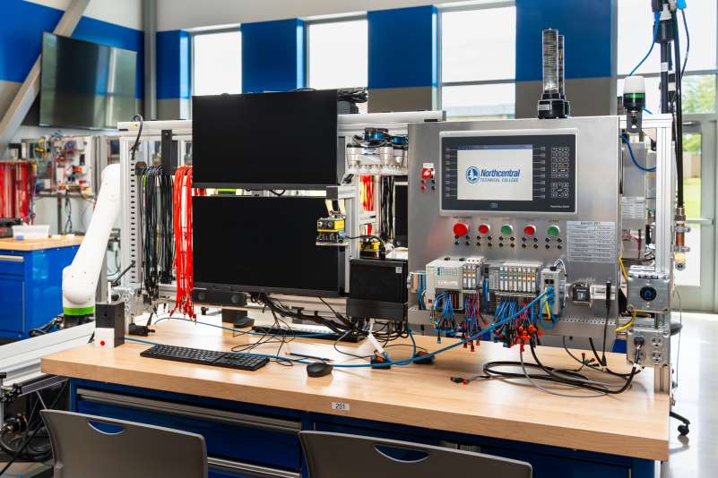 A workstation within the Industry 4.0 Smart Manufacturing Lab, with two monitors, robotics, and leads, along with a robotics panel displaying the NTC logo.
