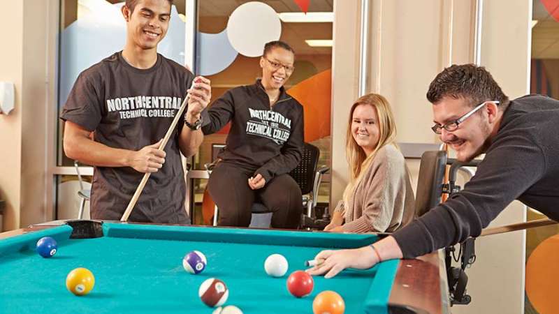 Students watch as two students play a game of Pool at The Den inside the Wausau Campus