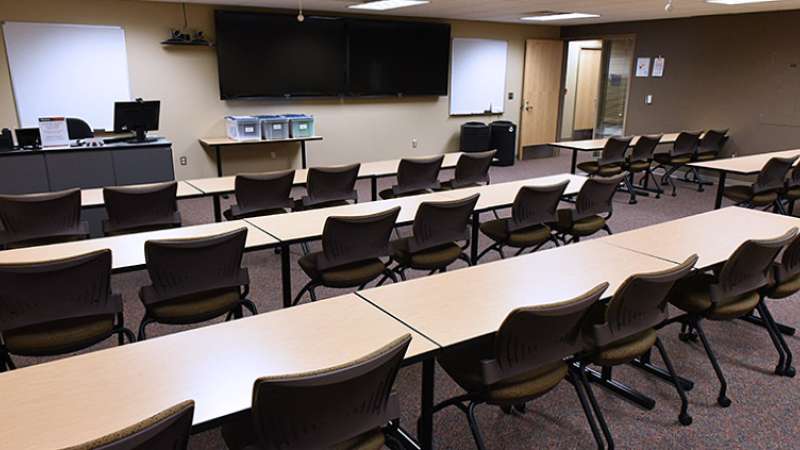 A training room with conference tables and chairs, as seen from the back of the room.