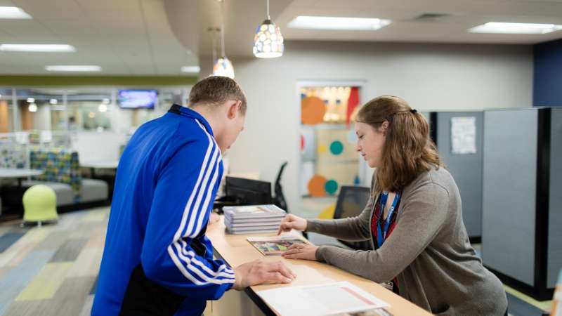 Staff member helps student find a program in a catalog.