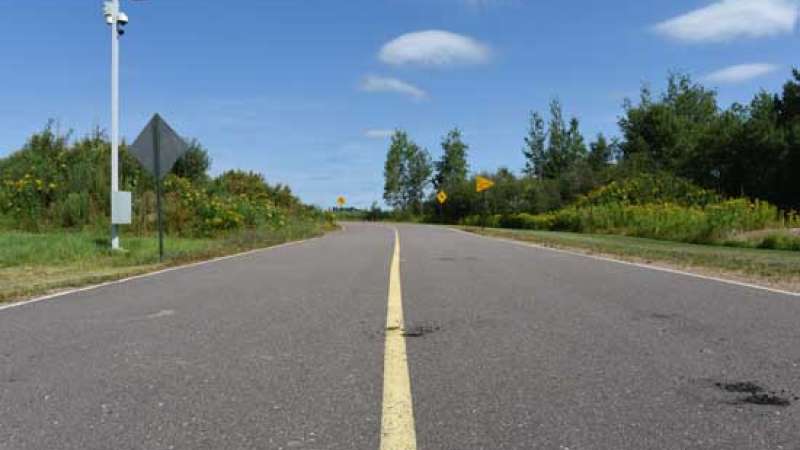 A paved roadway with one yellow stripe down the center.
