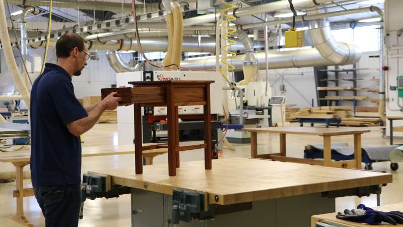 A student inspects his end table inside the Wood Technology Center of Excellence.
